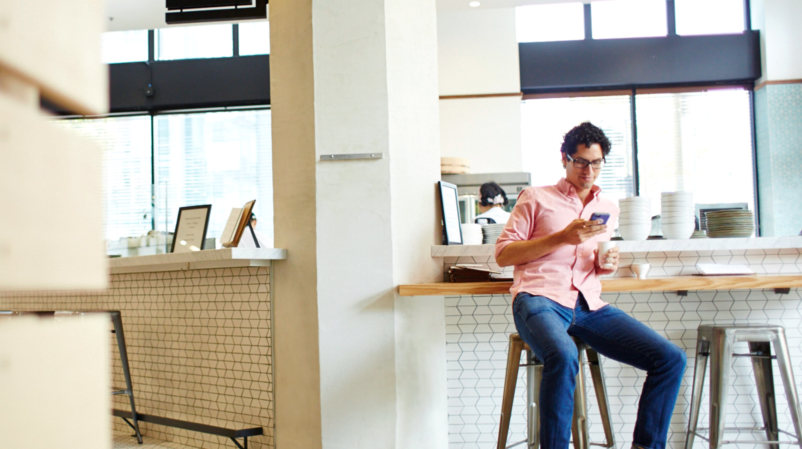 Man seated at café counter checking his phone.