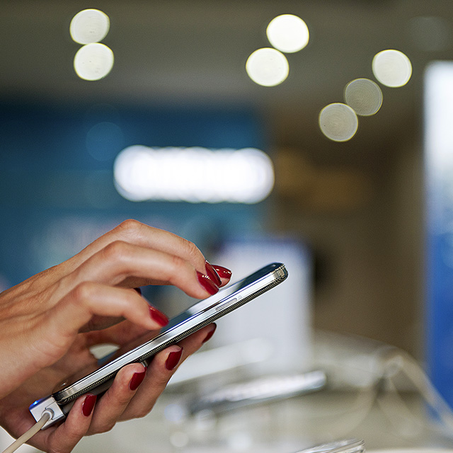 Close up of a woman with red fingernails using a mobile phone