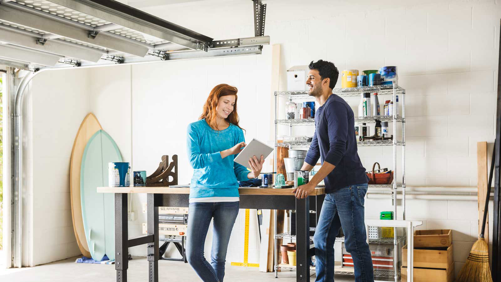 Visa - Person-to-person payments Happy man and woman talking while standing in a home garage and looking at a tablet.