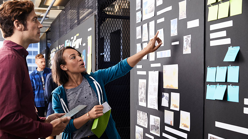 Man and woman discussing an item on a Scrum Task Board.